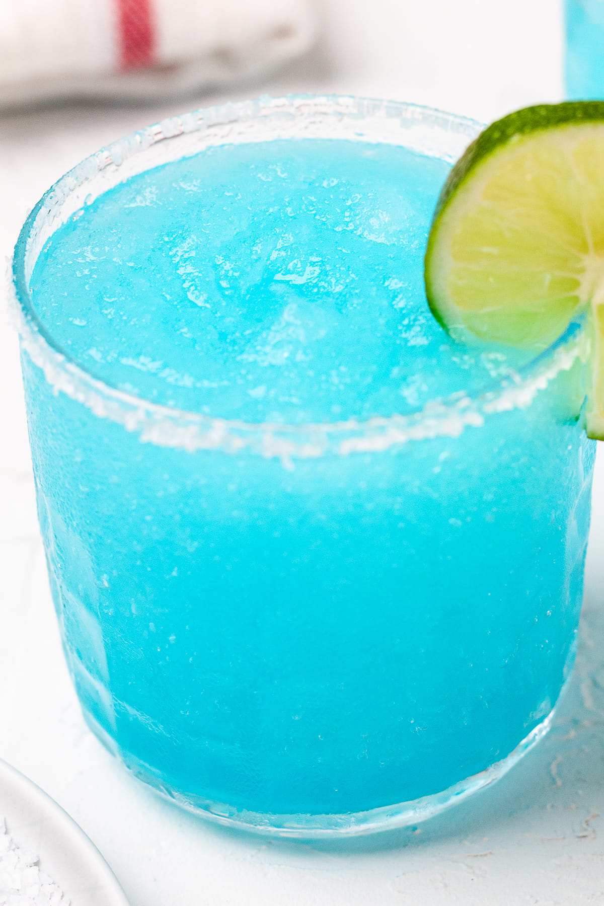 Up close image of frozen blue margarita with a slice of lime.