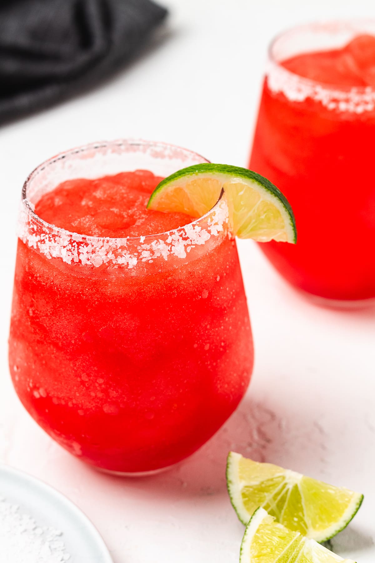Frozen red margarita with a salted rim and lime wedge garnish.