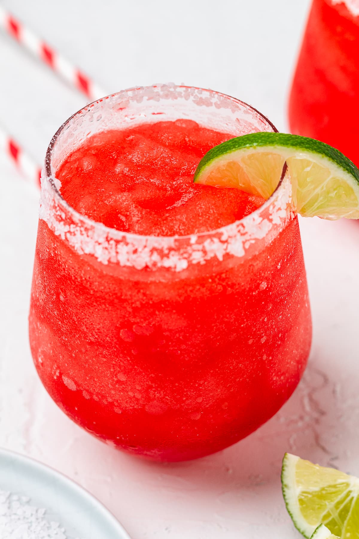 Frozen red margarita with a slice of lime in a salt rimmed glass.