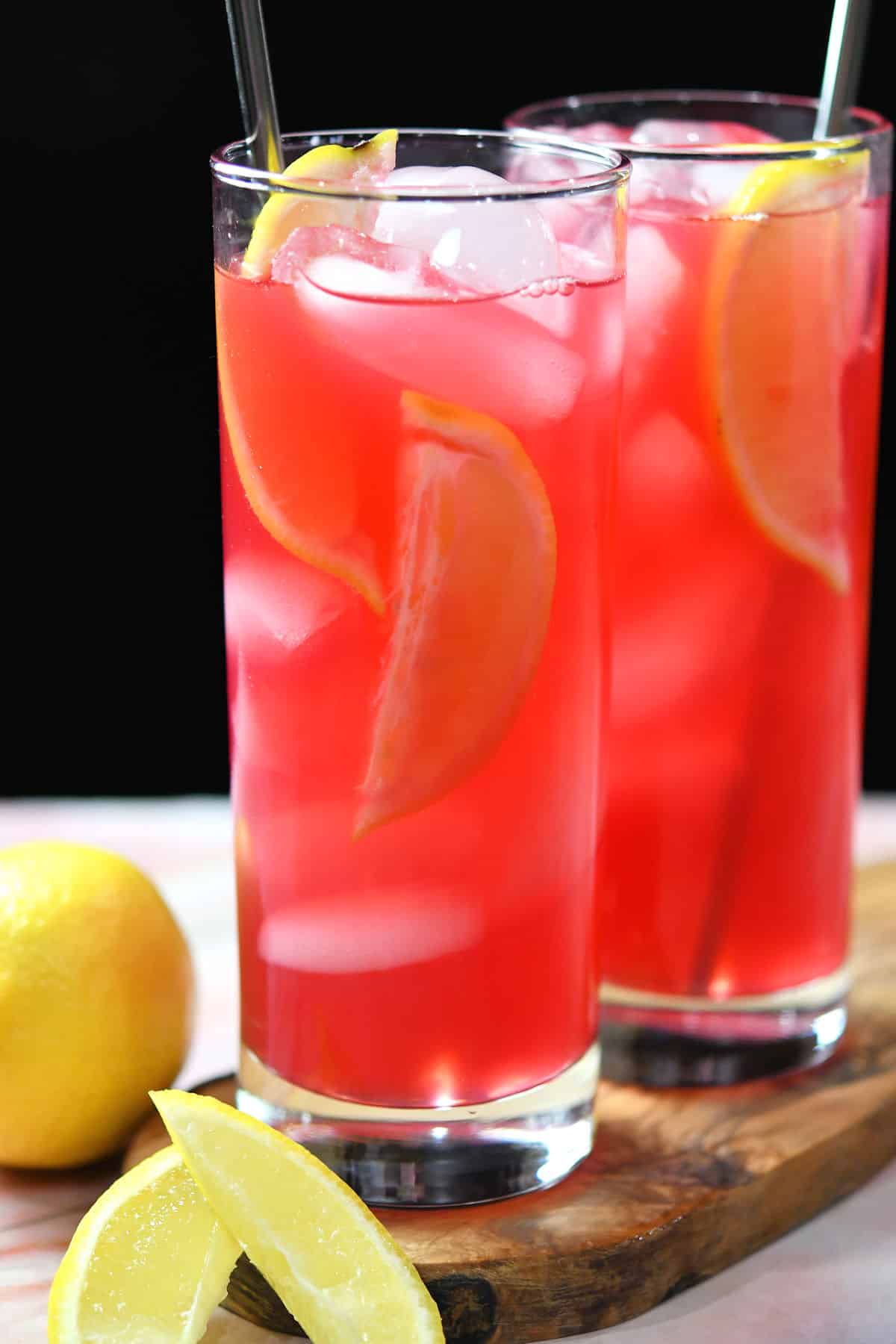 Hibiscus lemonade in glasses with lemon slices and bright red color.