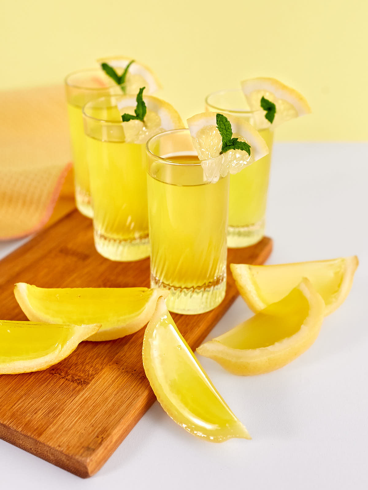 Lemon jello shots in small glasses with ice cubes on white background.