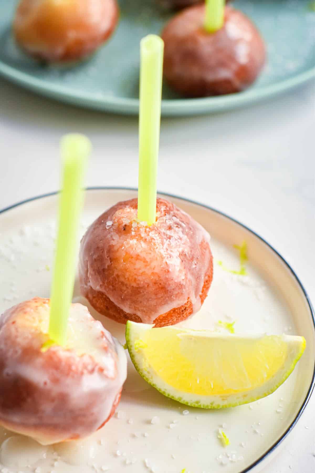 Glazed cake pops with lime wedge garnish on a plate.