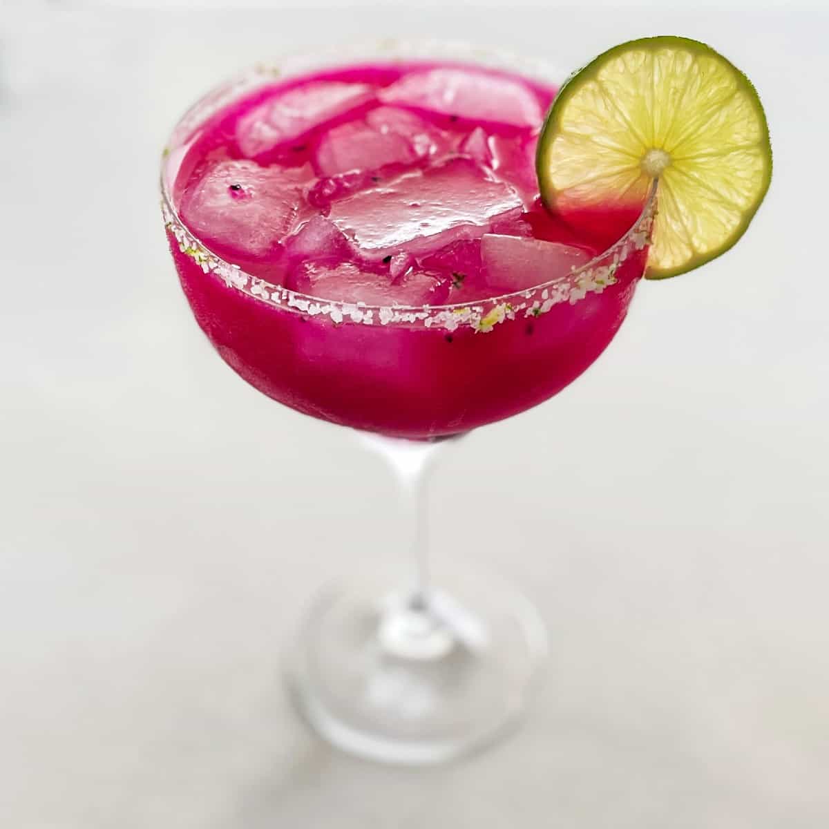 Dragon fruit margarita with vibrant pink color and lime wedge.