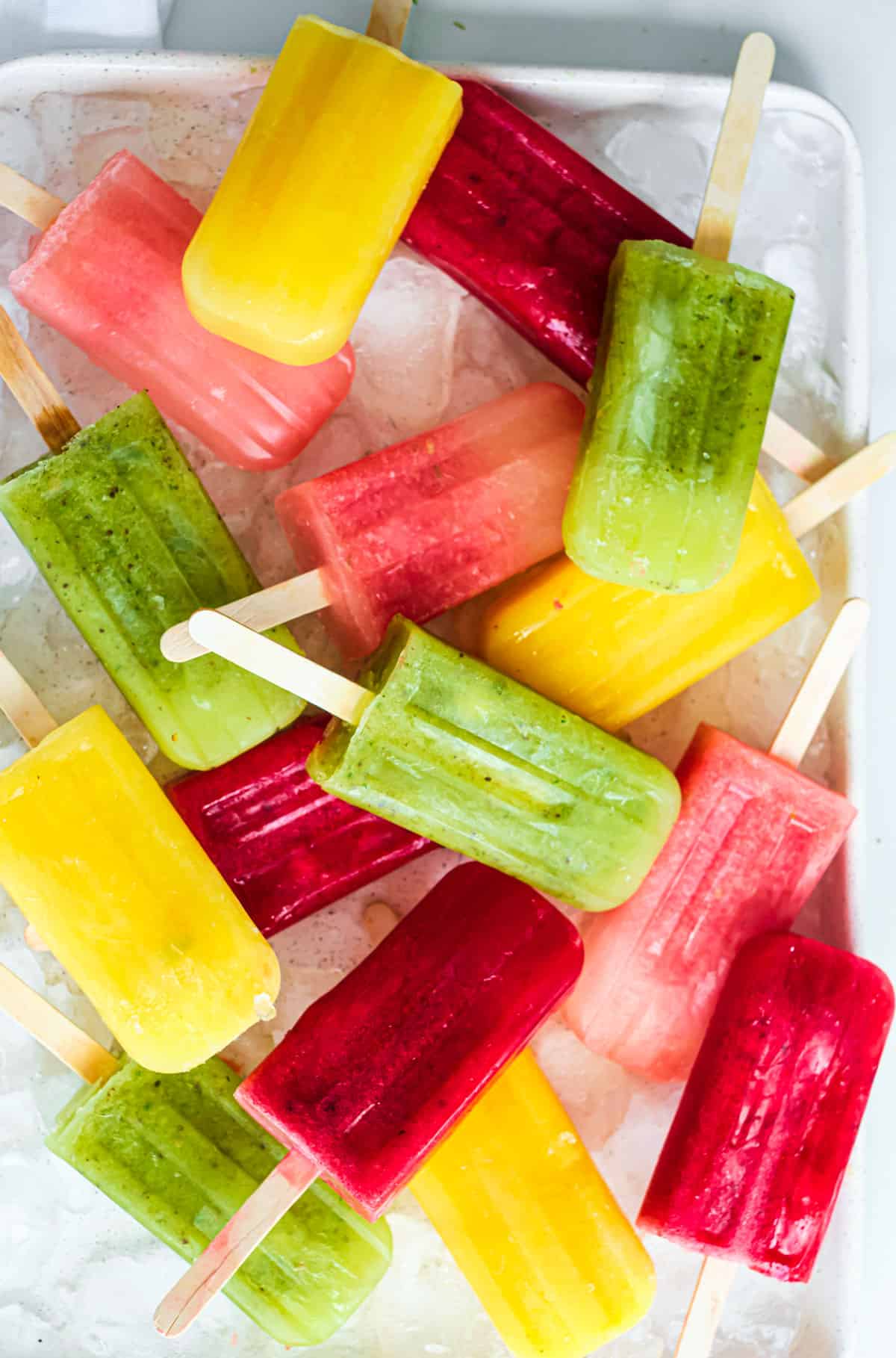 Colorful Mexican paletas in red, yellow, and green on ice.