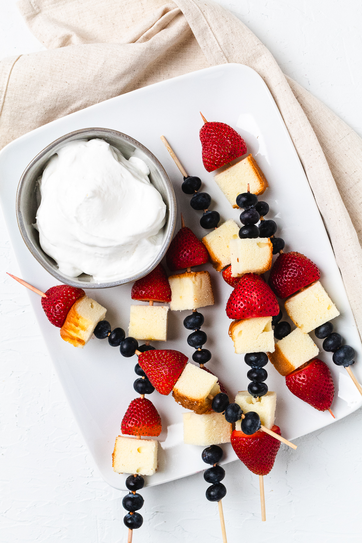 Overhead image of patriotic red, white, and blue pound cake skewers with whipped cream.