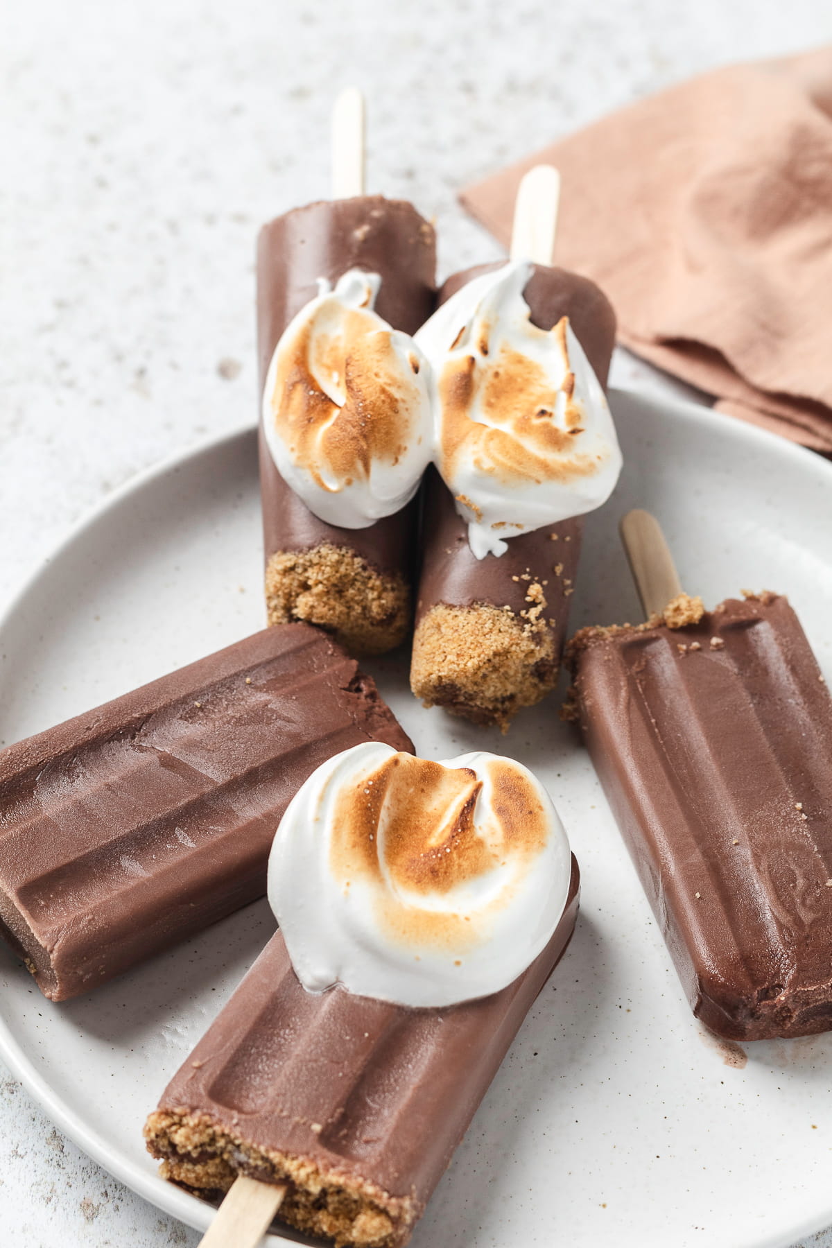 Chocolate s’mores popsicles topped with toasted marshmallow and graham crumbs.