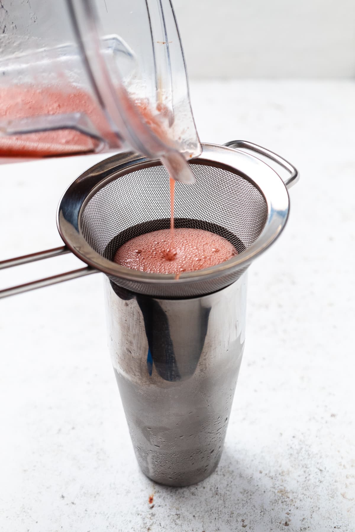 Blender container filled with reddish blended liquid with measurement markings on the side.