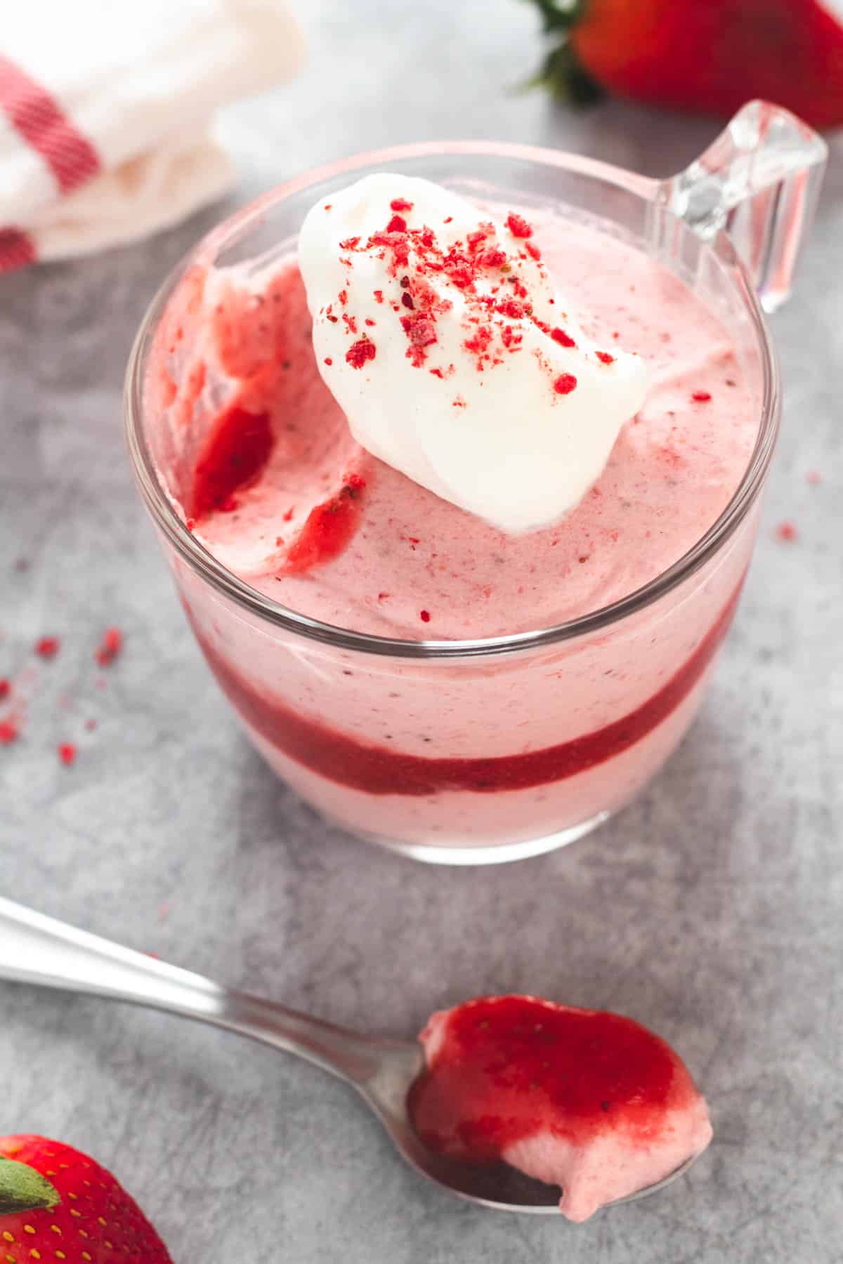 Strawberry mousse in glass topped with whipped cream and strawberry pieces.