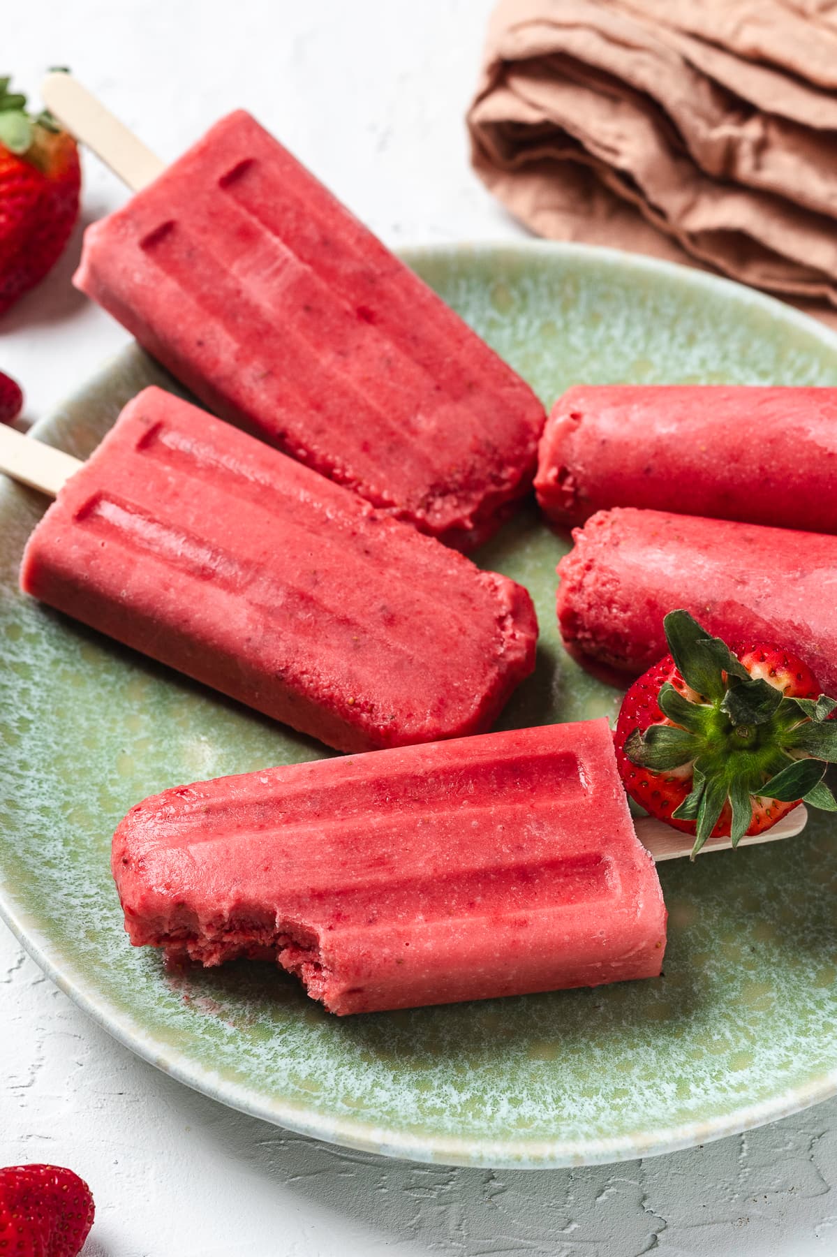 Strawberry popsicles of a green plate.