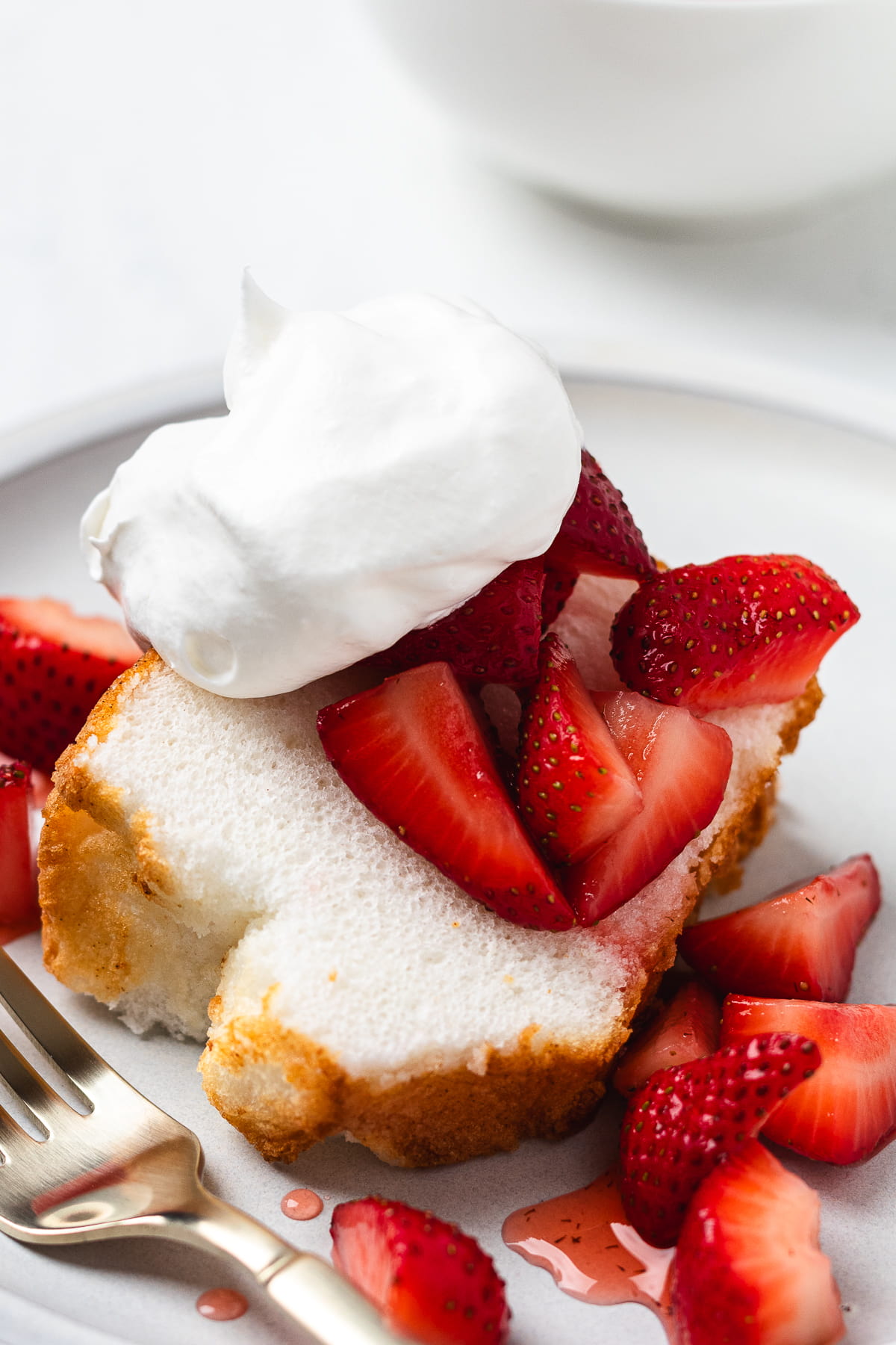 Close-up of strawberry shortcake with angel food cake, whipped cream, and juicy sliced strawberries.