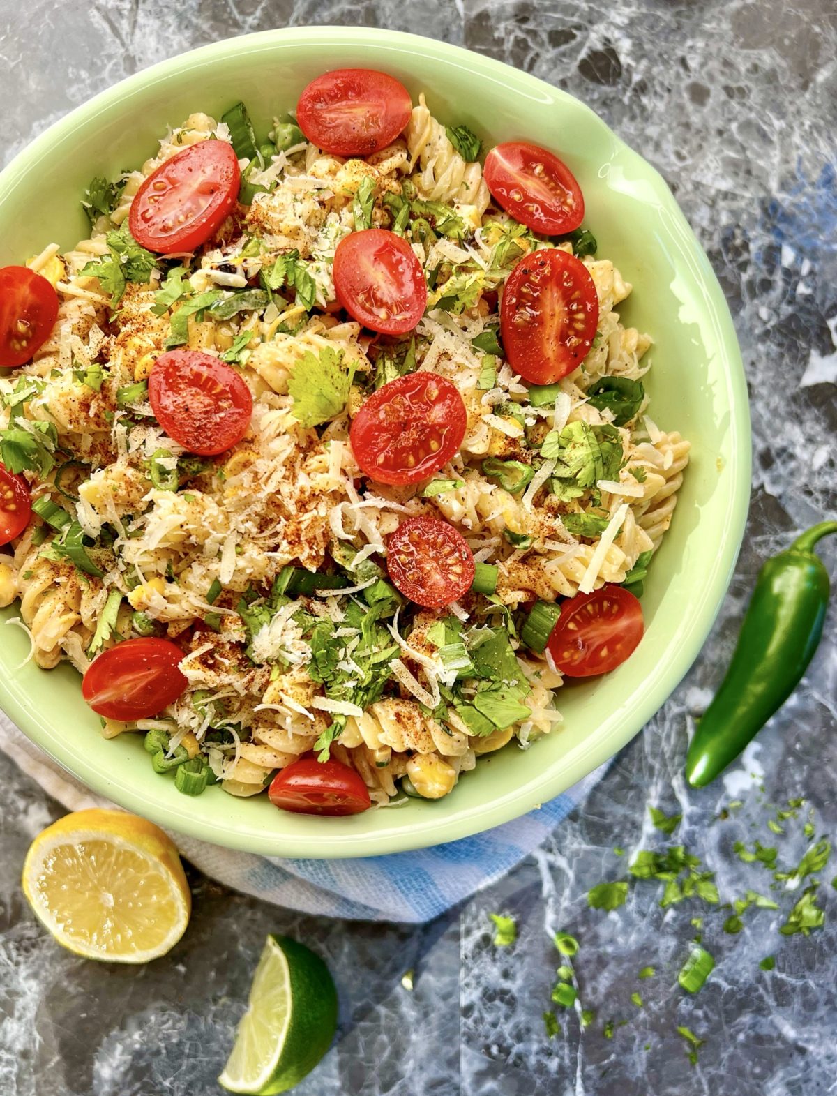 Mexican street corn pasta salad with cherry tomatoes, cilantro, cheese, and lime.