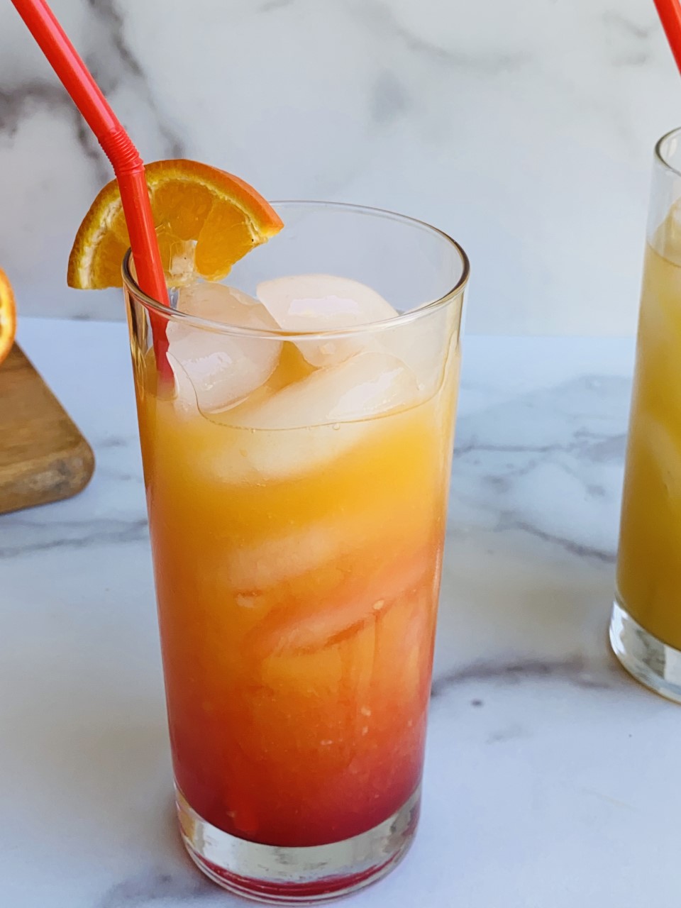 Tequila sunrise cocktail with orange and cherry gradient over ice.