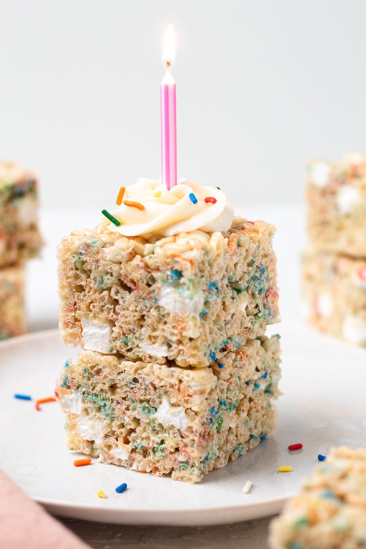 Birthday Cake Rice Krispie treats stacked with frosting, sprinkles, and a candle.