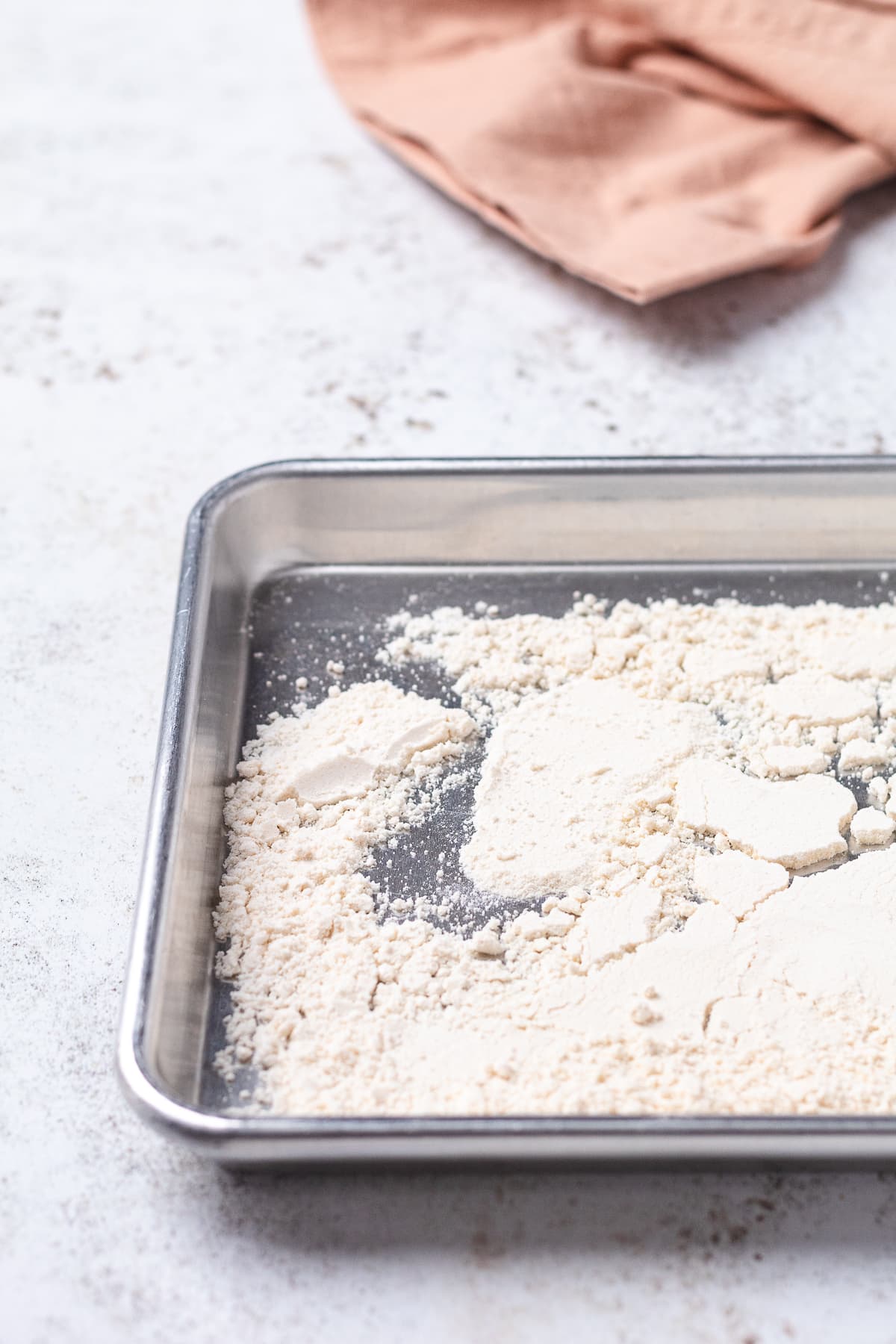 Heat-treated yellow cake mix spread on a baking sheet.