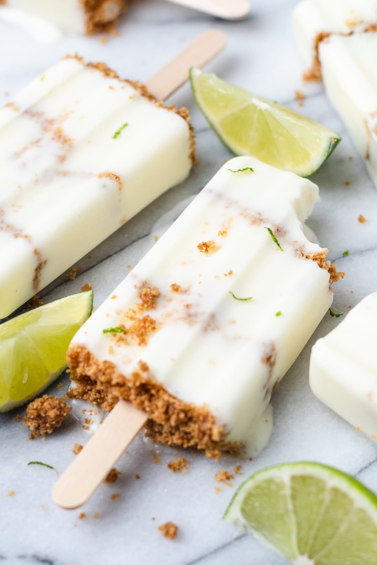 Key lime pie popsicle with graham cracker crumbs and lime wedges.
