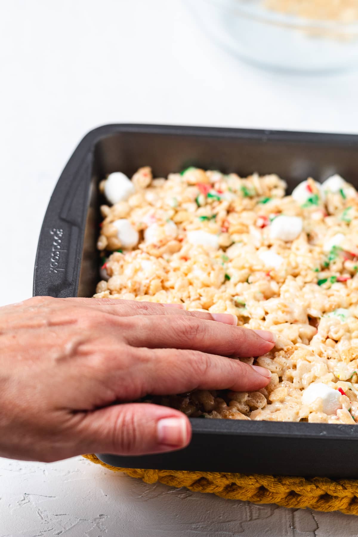 Pressing Christmas Rice Krispie treat mixture into a pan.