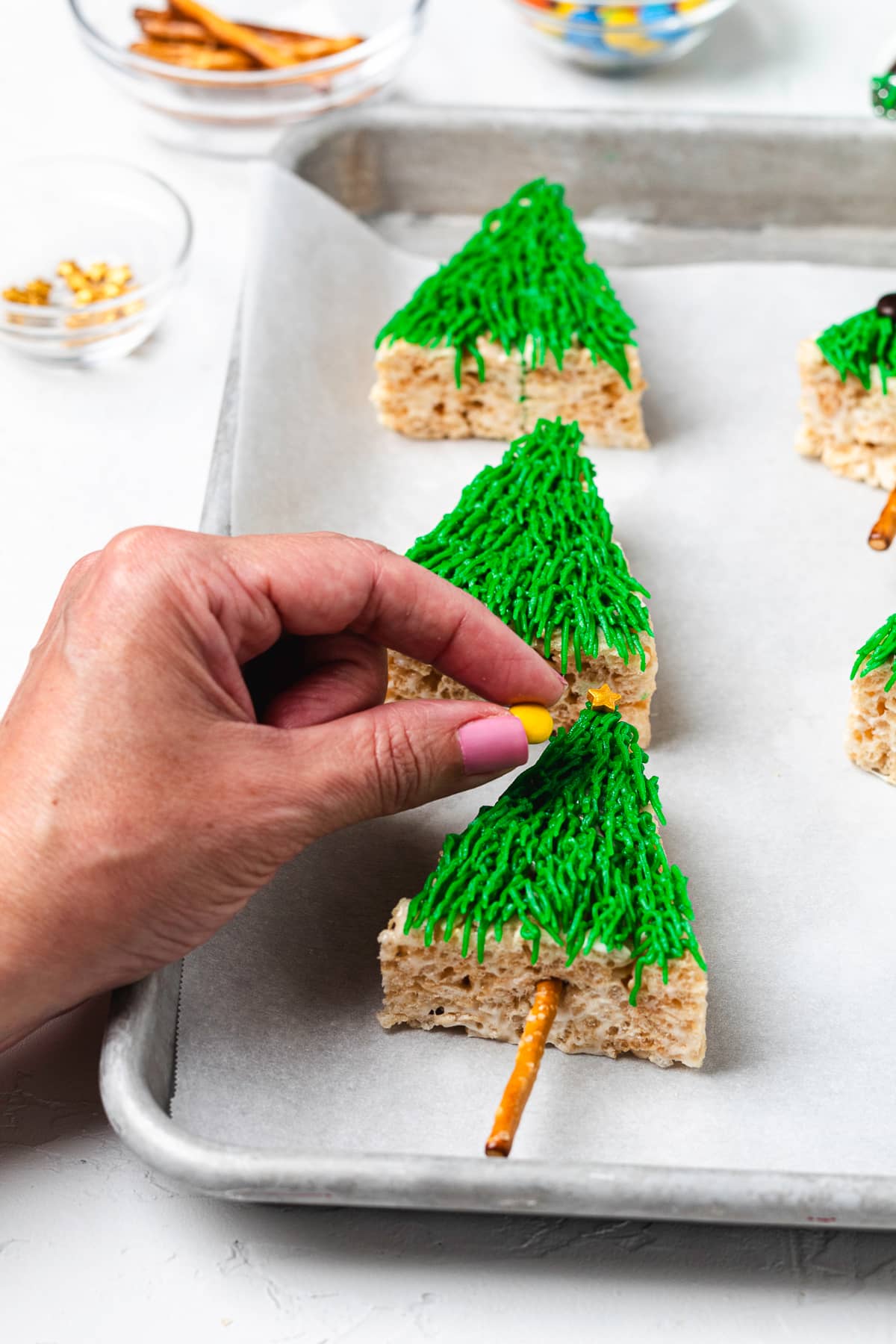 Adding candies to Christmas tree Rice Krispie treat.