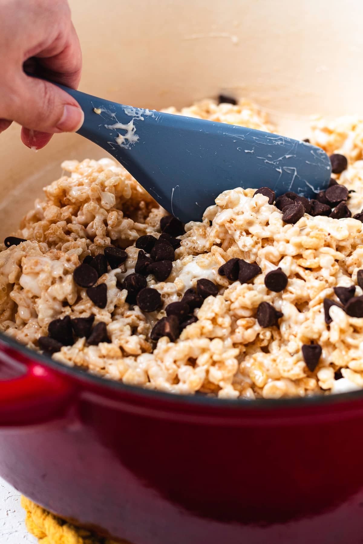 Folding chocolate chips into the Rice Krispie treat mixture.
