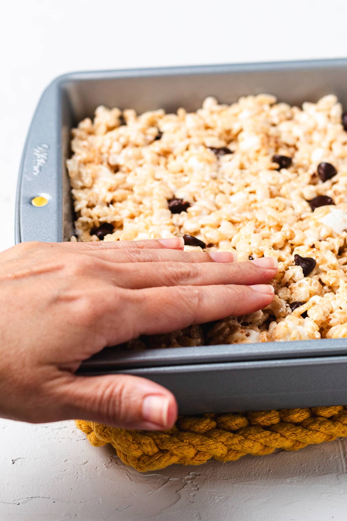 Pressing Rice Krispie treat mixture into a baking pan.