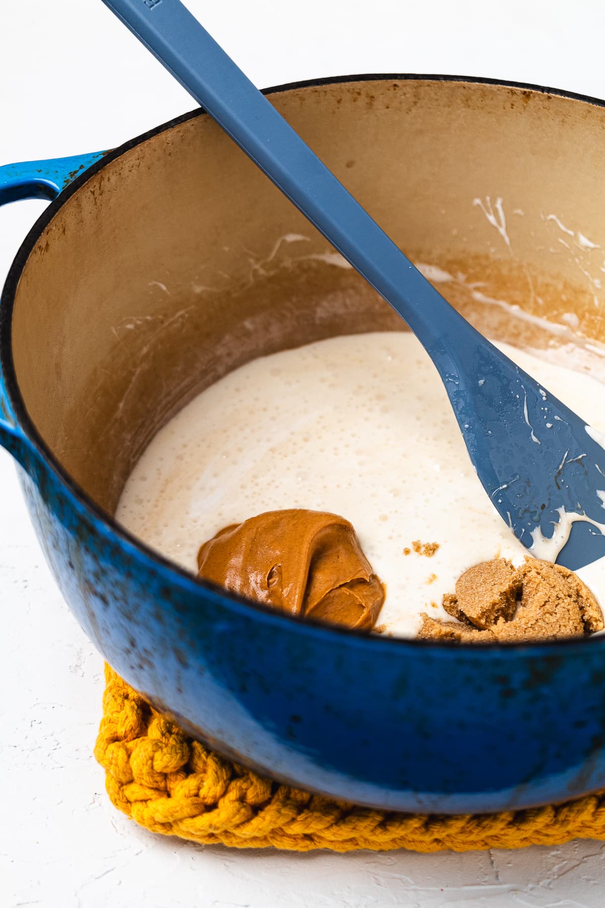 Peanut butter, brown sugar, milk, and marshmallows in a Dutch oven before being stirred together.