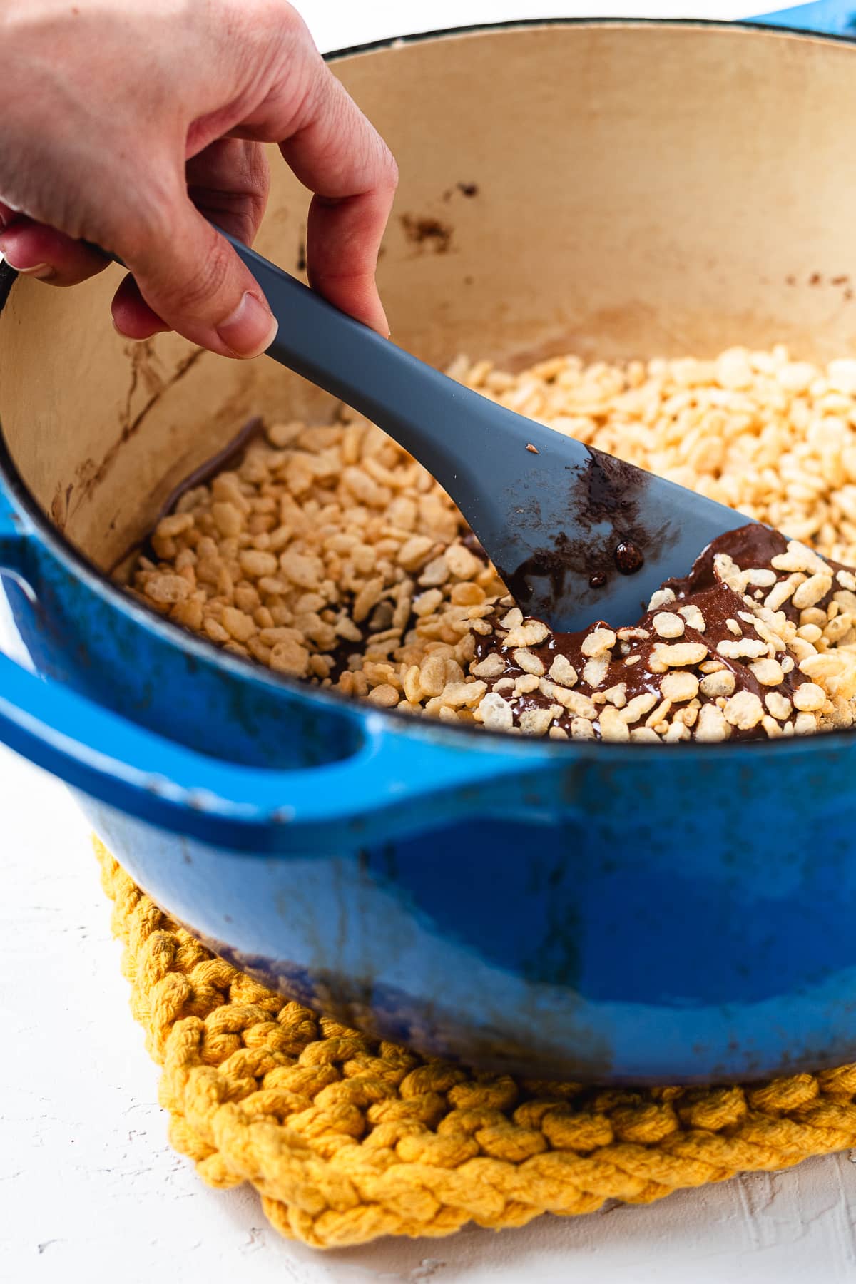 Mixing Rice Krispies into the chocolate marshmallow mixture.