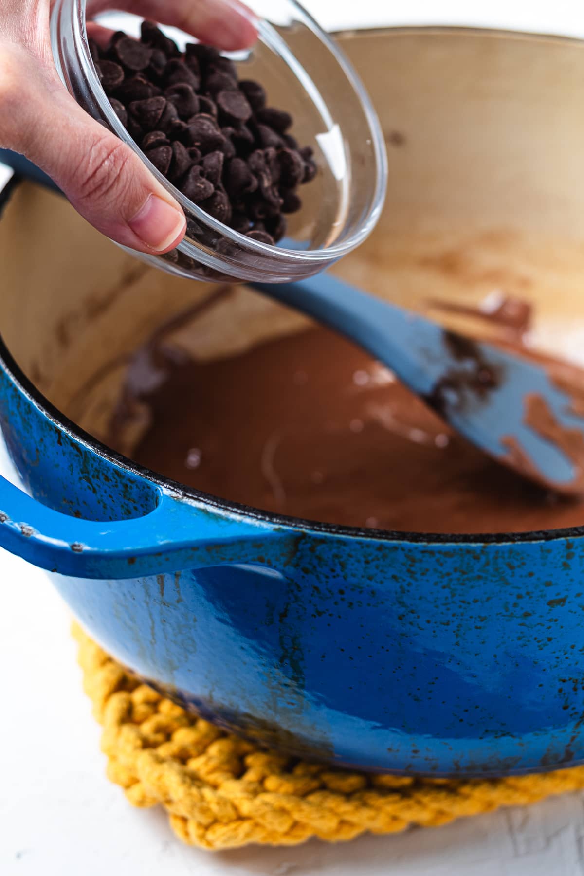 Adding chocolate chips to the melted chocolate mixture.