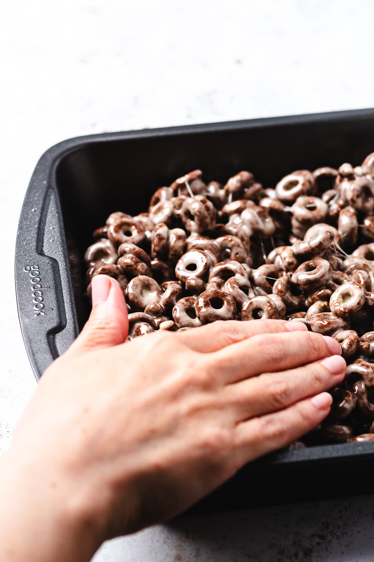 Pressing Cocoa Loops crispy treats into a baking pan.