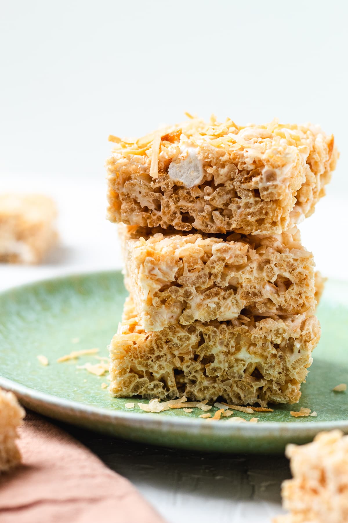 Stack of coconut Rice Krispie treats on a green plate.