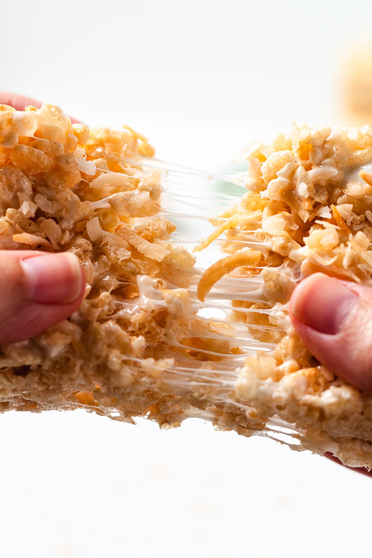 Coconut Rice Krispie treat pulled apart with melted marshmallow stretch.