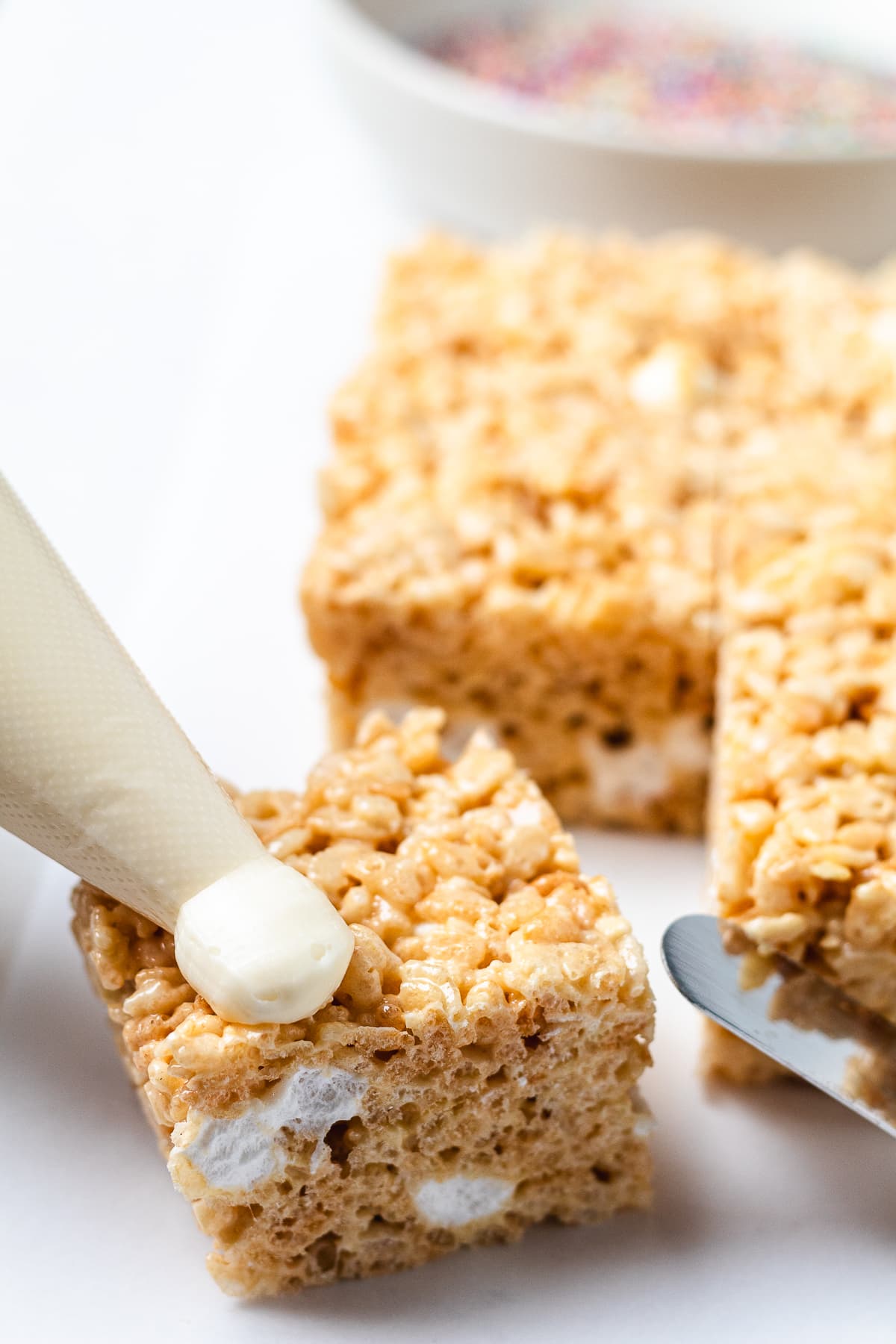 Spreading frosting onto a Rice Krispie treat.
