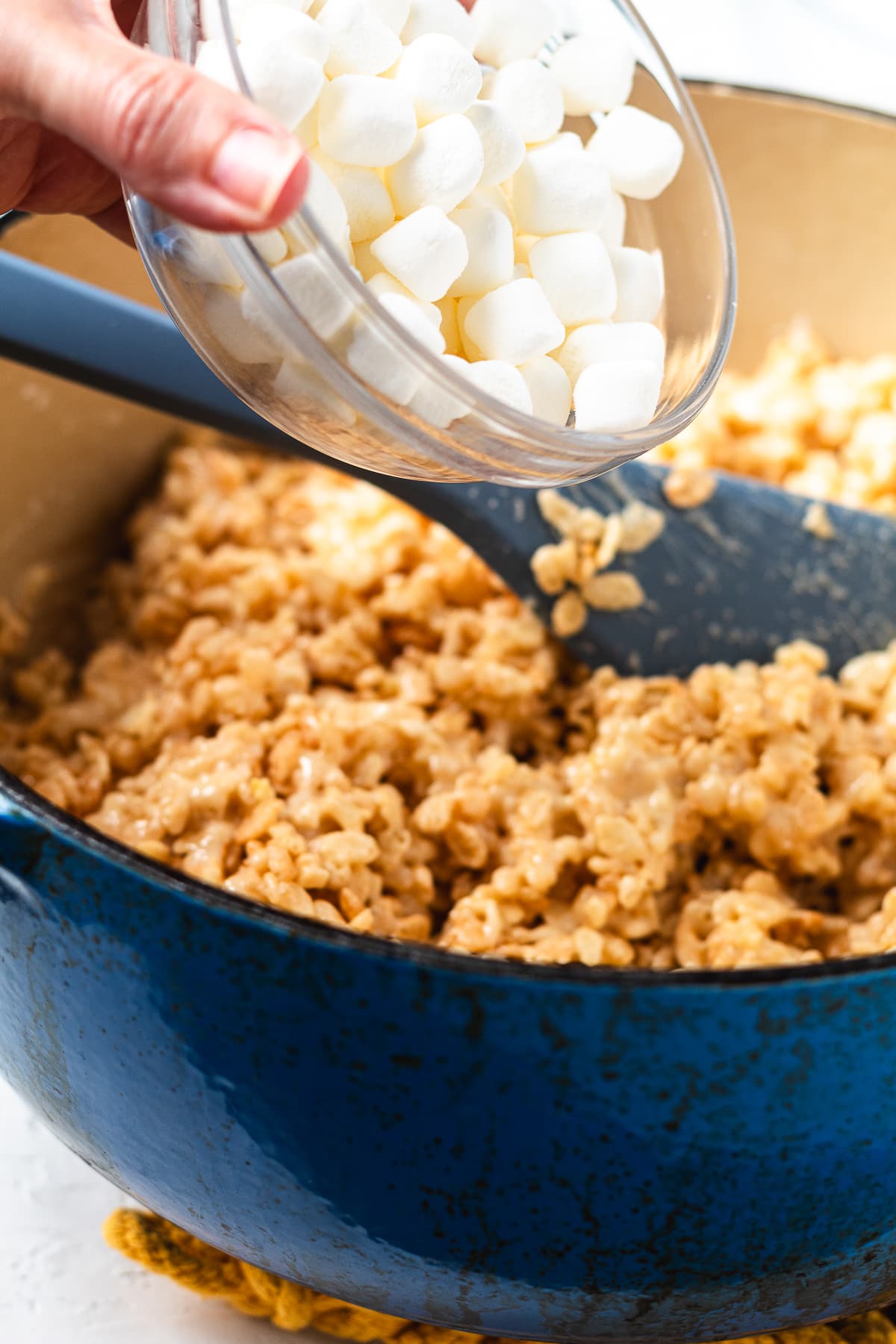 Folding mini marshmallows into the cereal mixture.