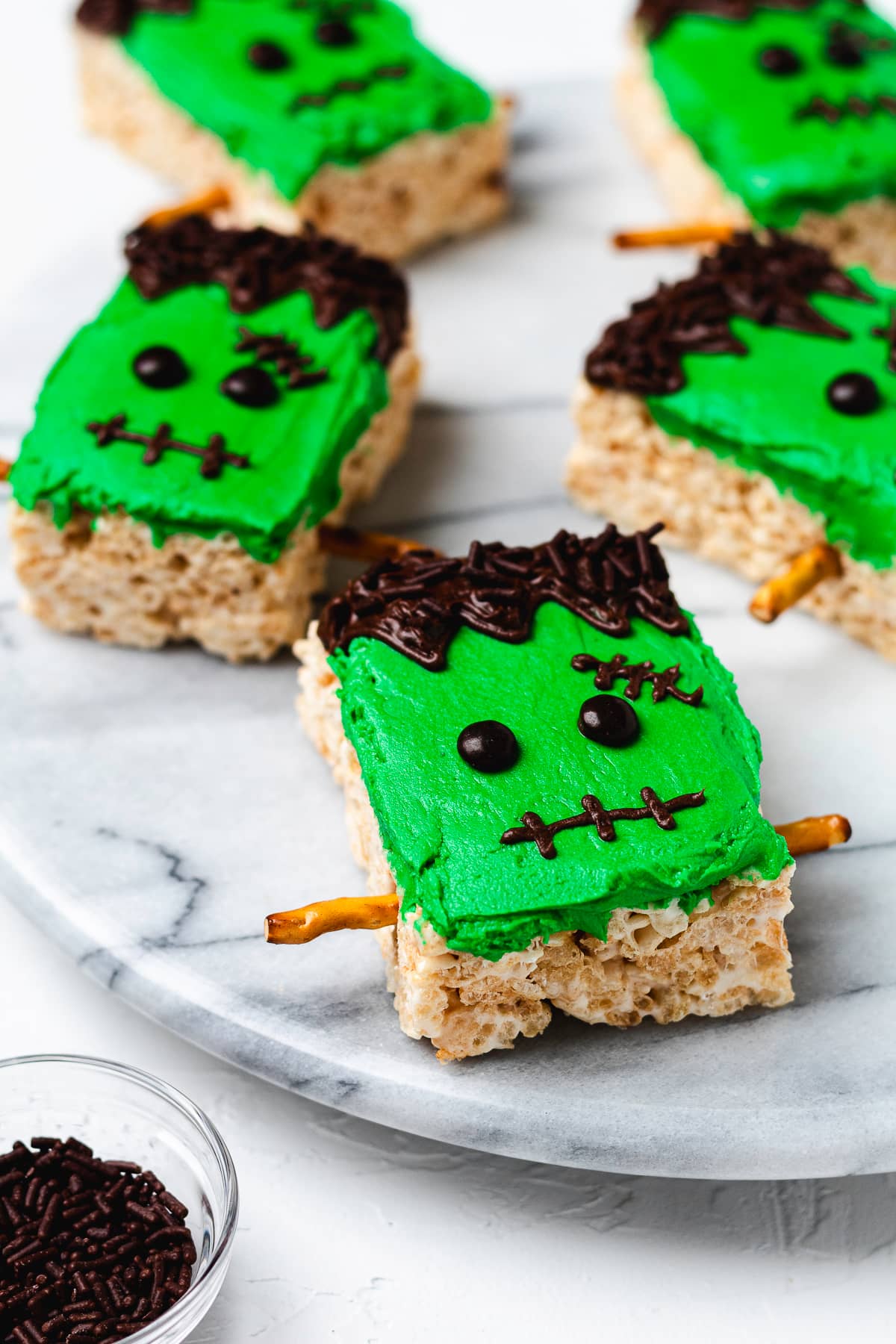 Frankenstein Rice Krispie treats decorated with green frosting, chocolate hair, and pretzel bolts.