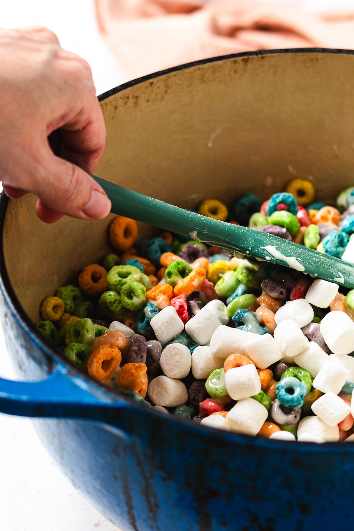 Adding mini marshmallows to Froot Loops cereal mixture.