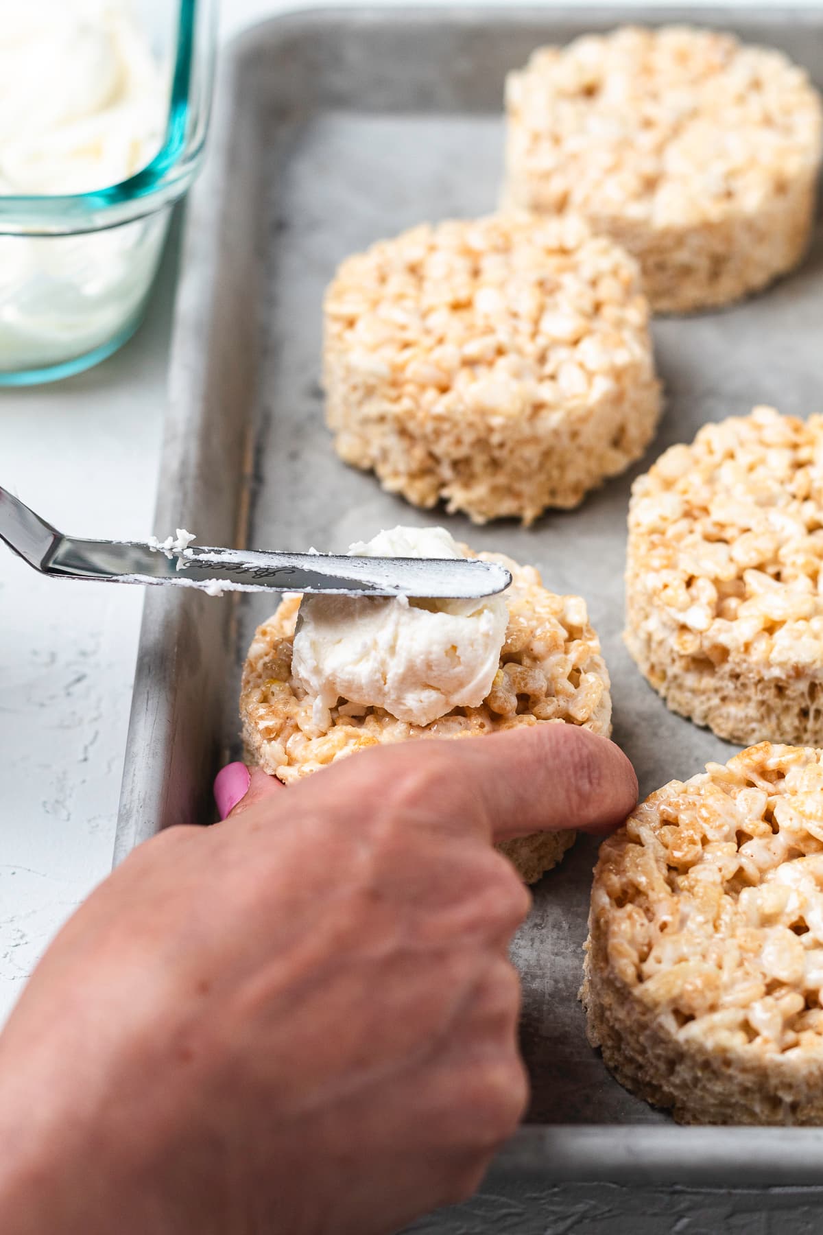 Spreading frosting onto a Rice Krispie treat with an offset spatula.