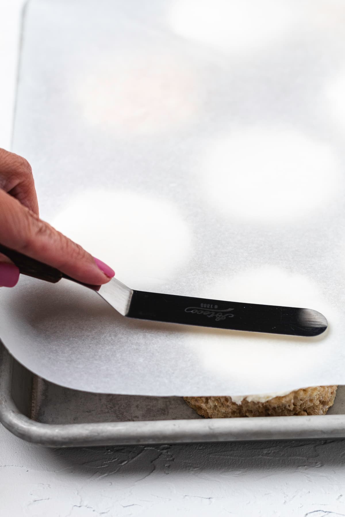 Smoothing frosting on a Rice Krispie treat with parchment paper.