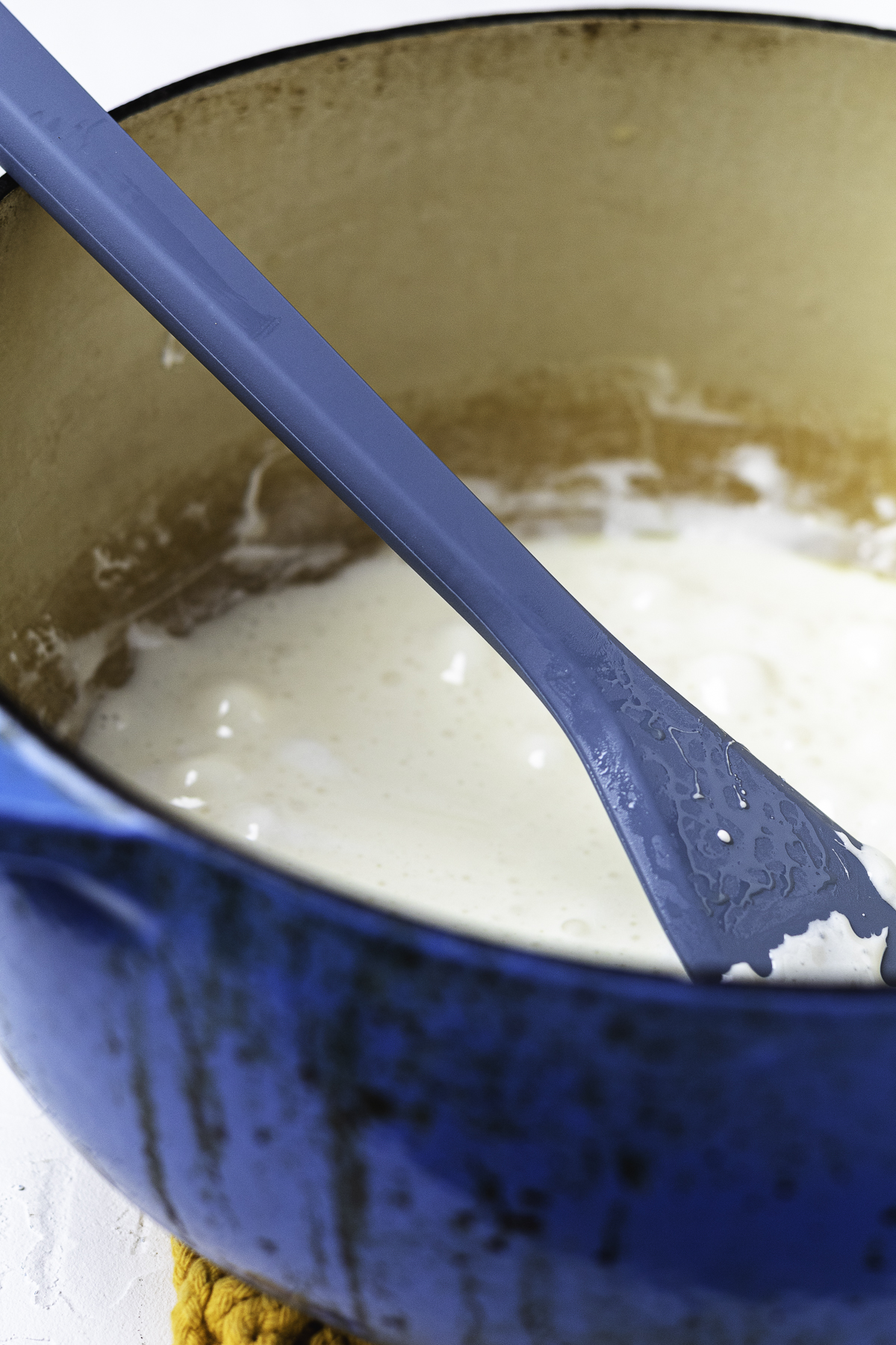 Mixing melted marshmallow in a blue Dutch oven.