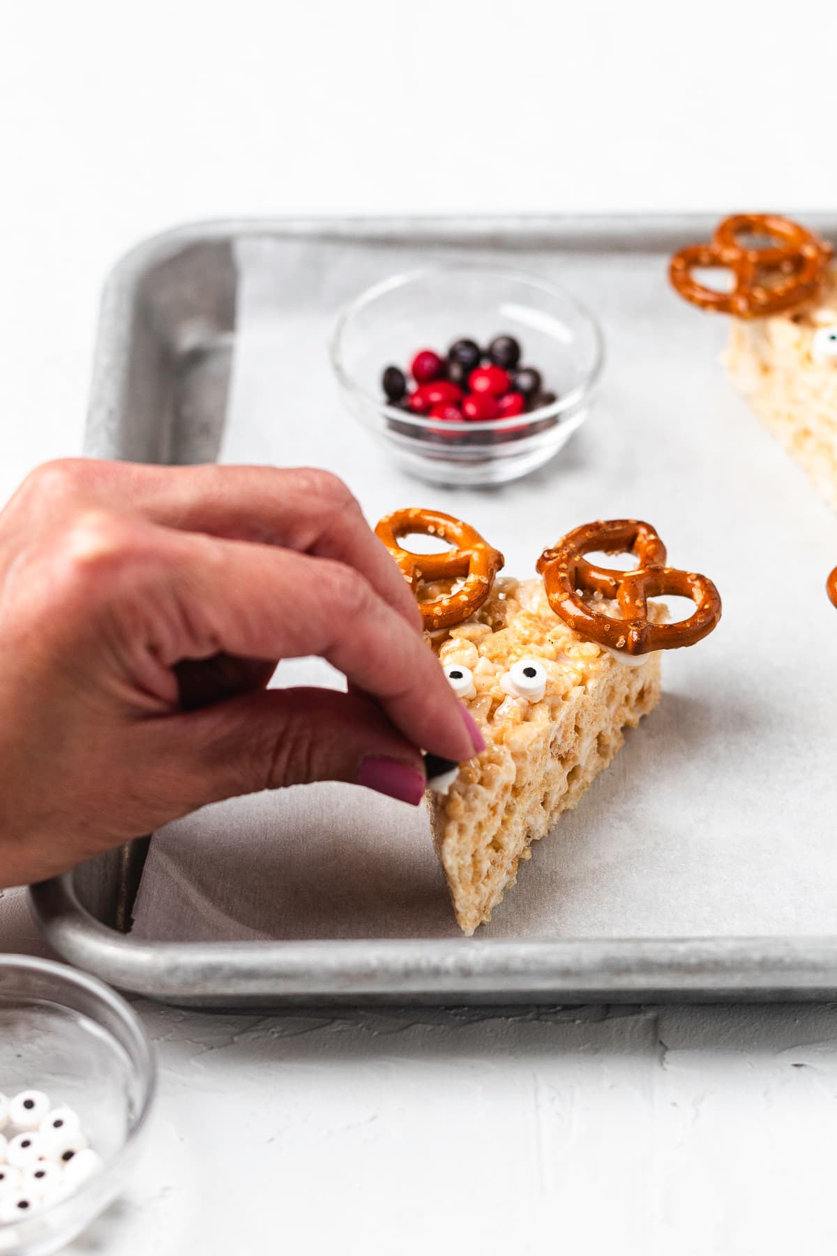 Adding a candy nose to a reindeer Rice Krispie treat.
