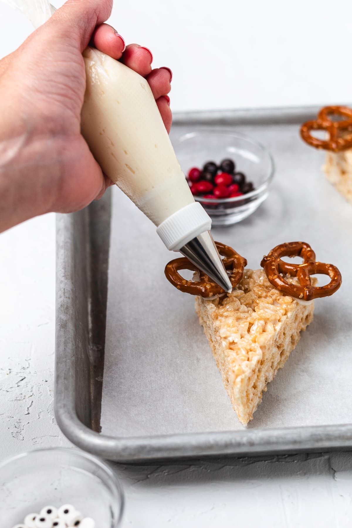 Piping frosting onto a reindeer Rice Krispie treat.