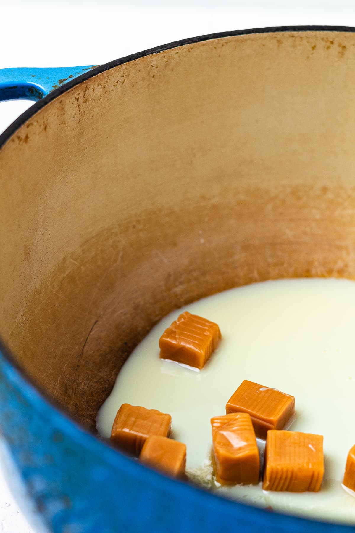 Sweetened condensed milk and caramels melting in a Dutch oven.