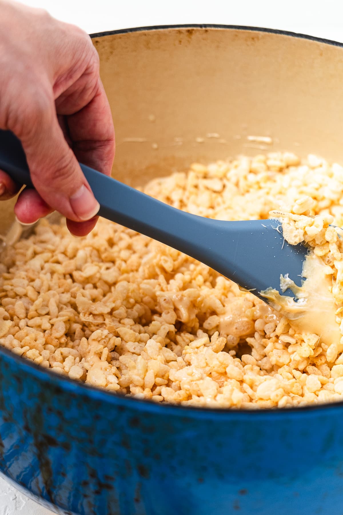 Mixing caramel marshmallow mixture with Rice Krispies cereal.