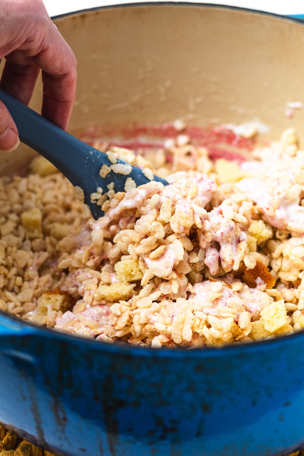 Mixing Rice Krispie cereal, marshmallows, and pound cake for strawberry shortcake Rice Krispie treats.