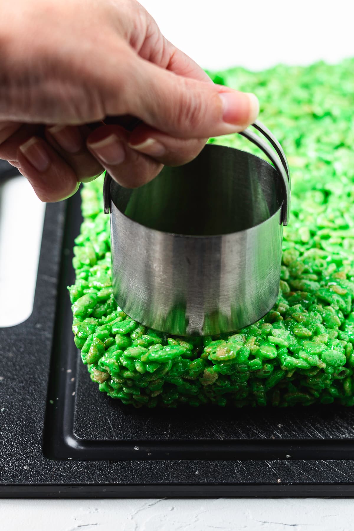 Cutting circles from a pan of green Rice Krispie treats.