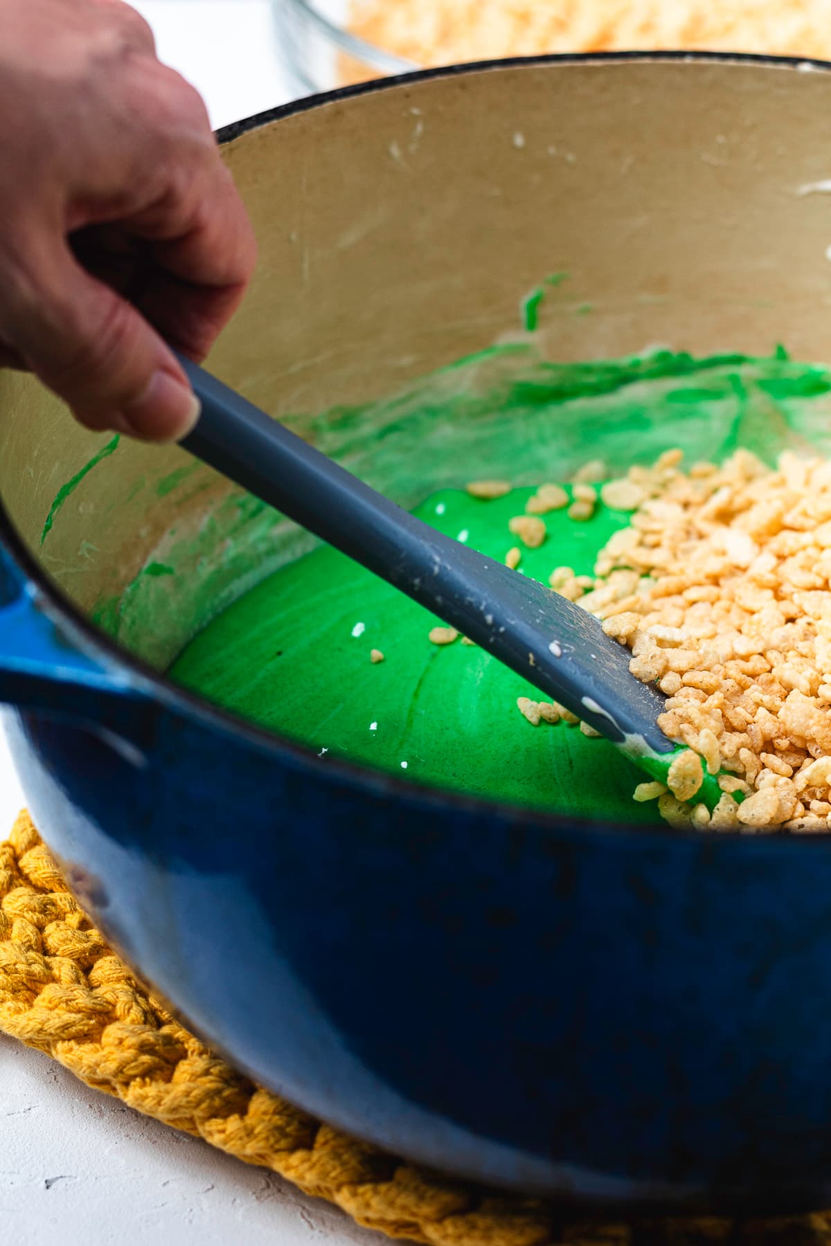 Mixing Rice Krispies cereal into the green marshmallow mixture.