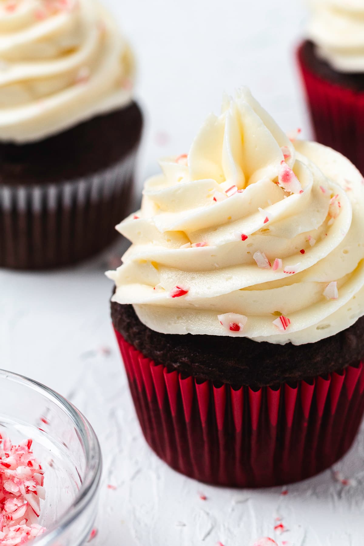Close-up of a chocolate cupcake topped with swirled peppermint frosting and crushed candy canes.