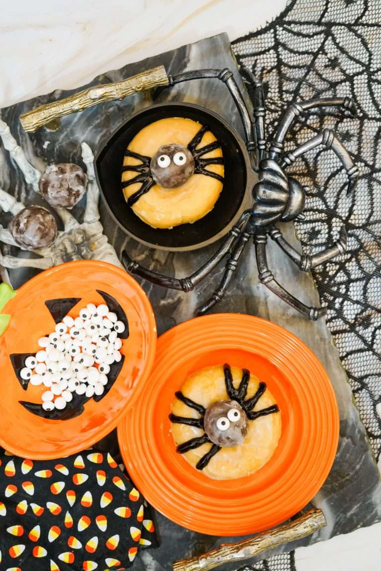 Overhead view of spider donuts with Halloween decorations in the background.