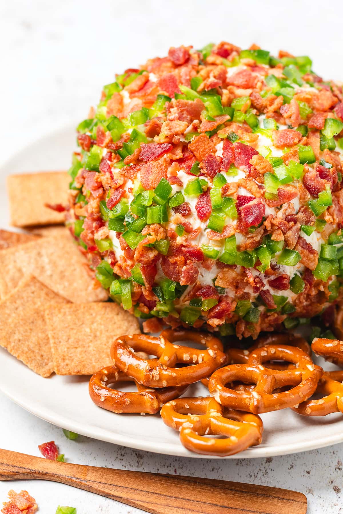 Bacon jalapeño cheese ball covered in crispy bacon and fresh jalapeños, served with crackers and pretzels.