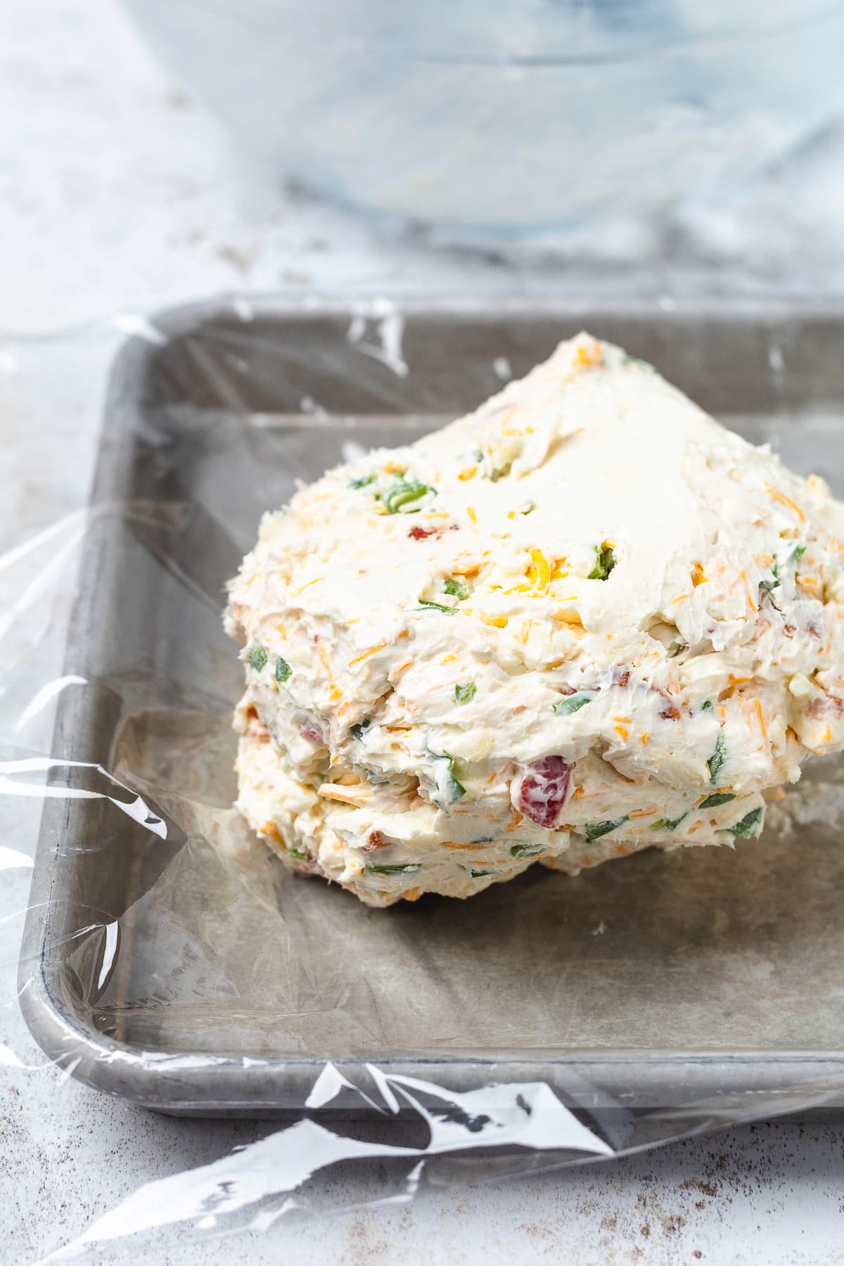 Bacon jalapeño cheese ball mixture on plastic wrap, ready to be shaped and chilled.