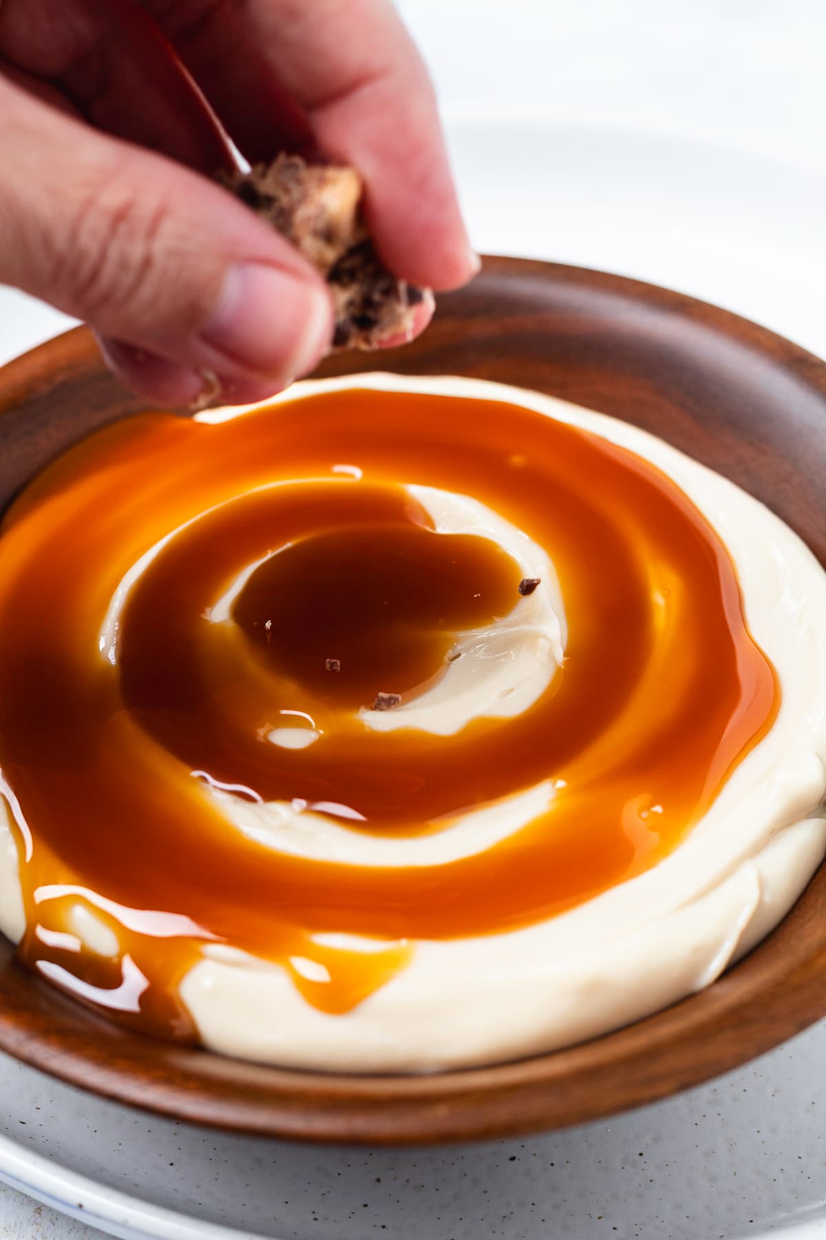 Sprinkling chopped Heath bars over creamy cheesecake dip topped with caramel sauce.