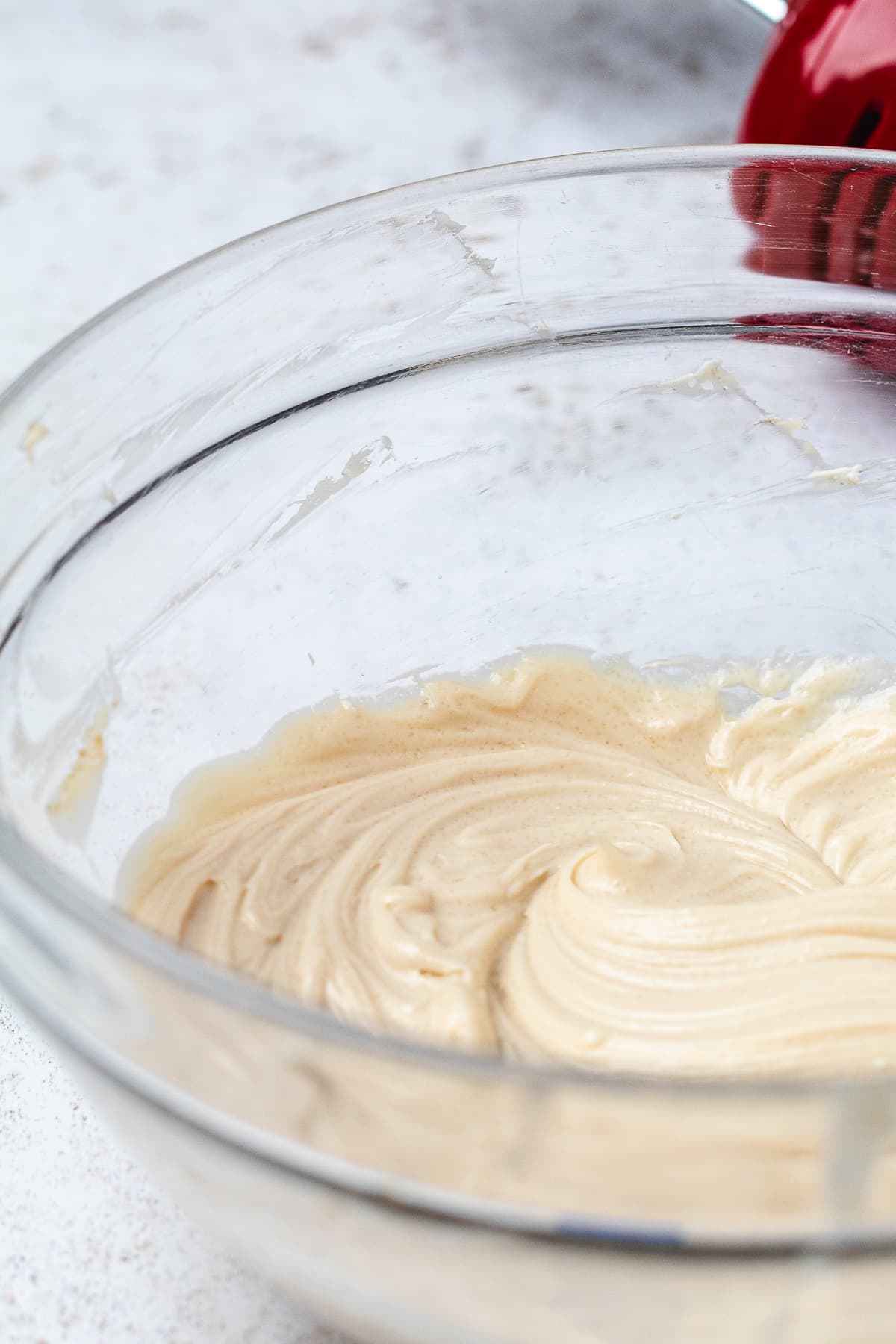 Close-up of the smooth, creamy caramel apple dip mixture in a clear glass mixing bowl.