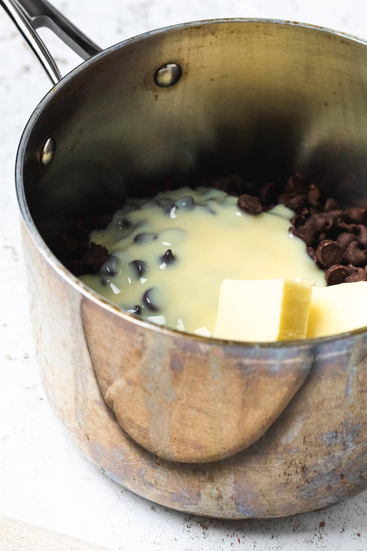 Chocolate chips, condensed milk, and butter in a saucepan, ready to melt.
